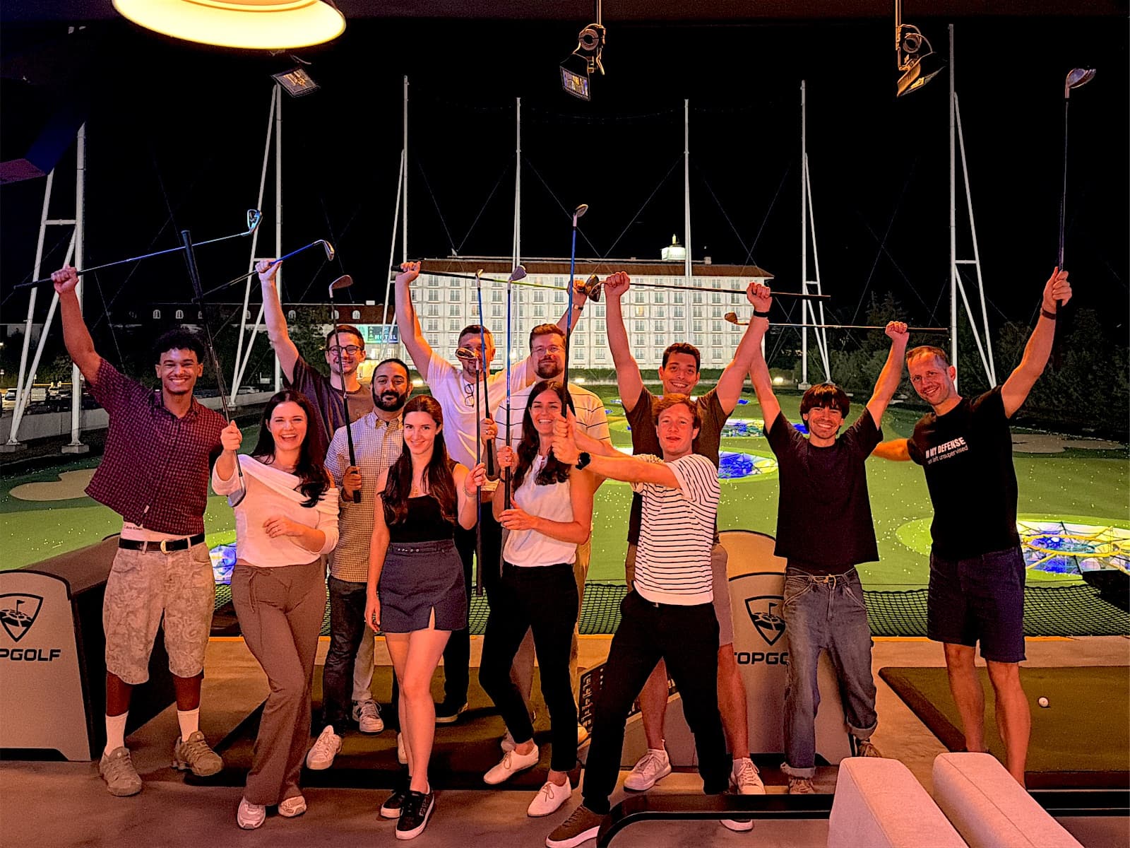 The Senseven team raising golf clubs at a team event at Topgolf