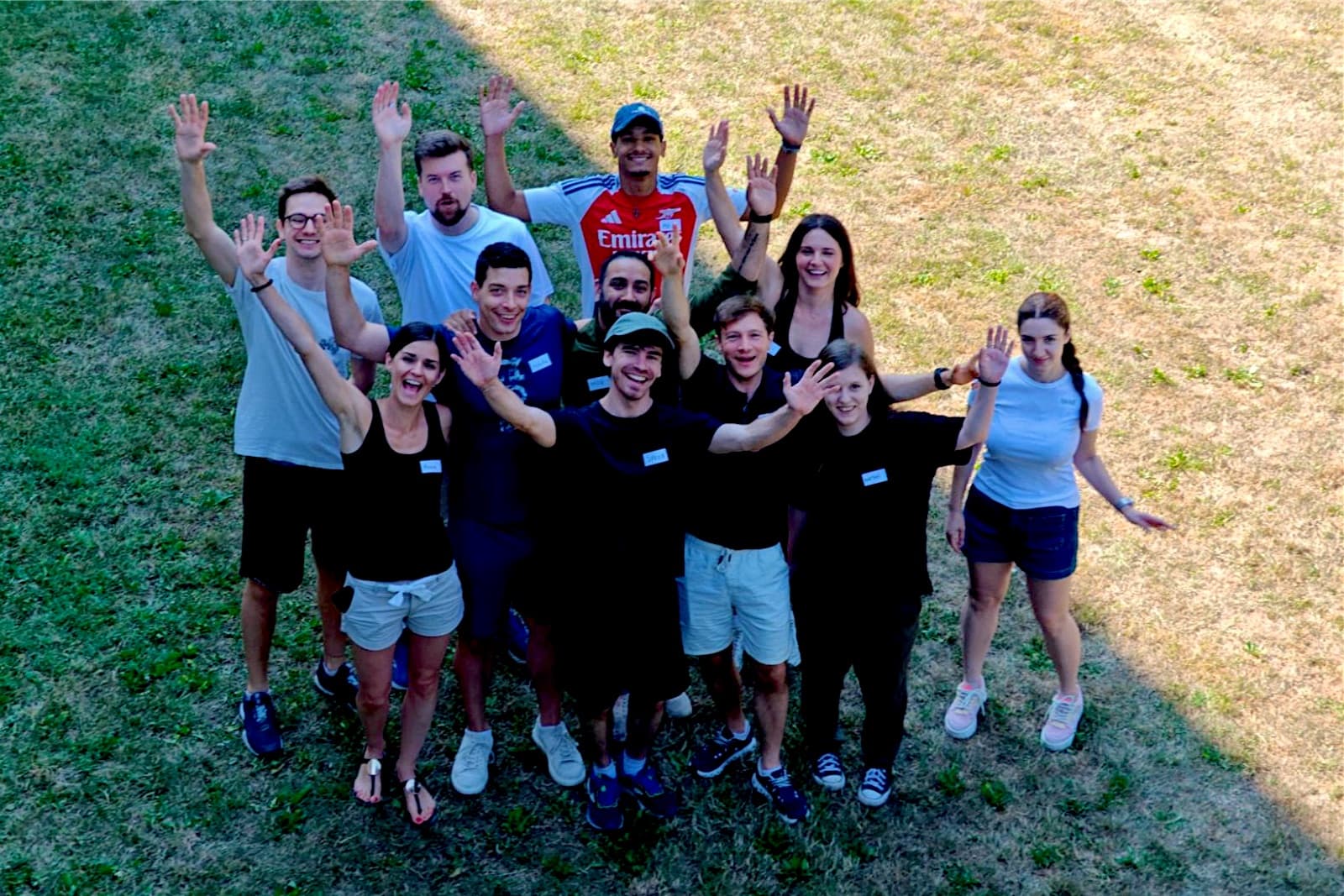 The Senseven team standing on a lawn and waving at the camera, photographed from above